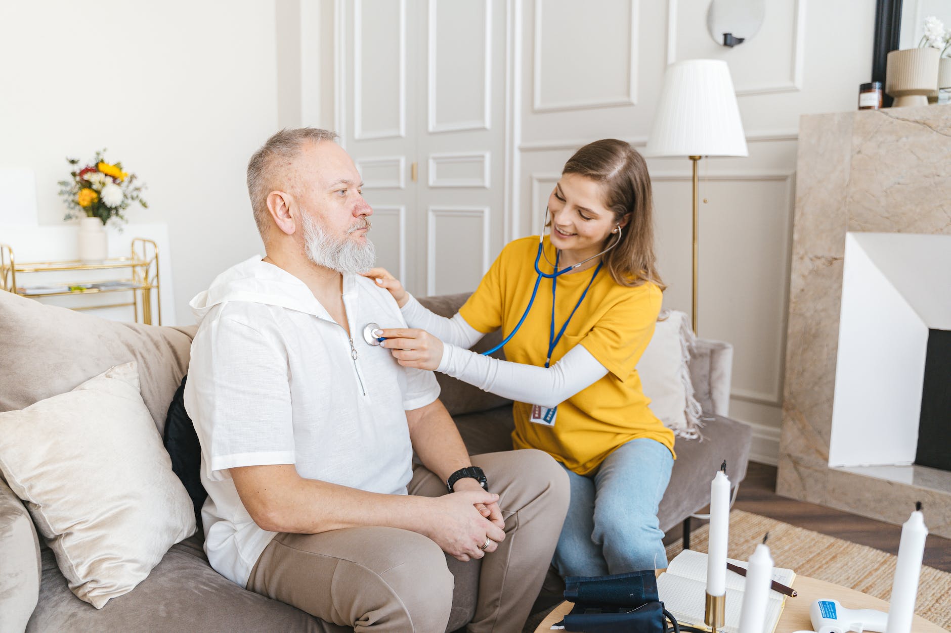 a woman in yellow shirt using a stethoscope on a man in a white shirt